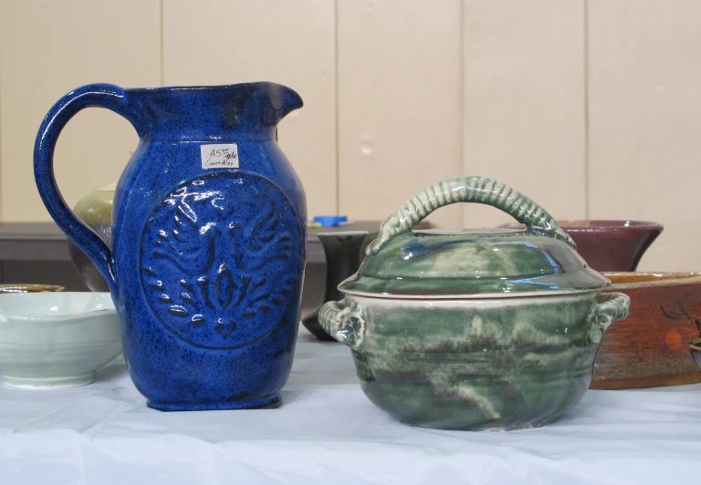 two different sized pottery on a table with a white cloth