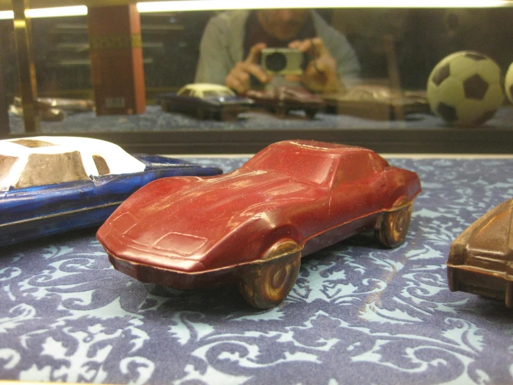 toy cars on a table while a man takes a po