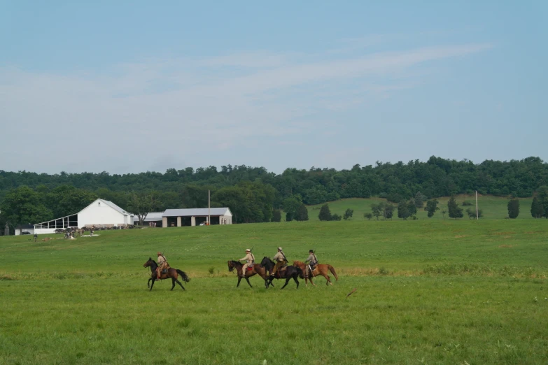 four people on horseback galloping around the farm