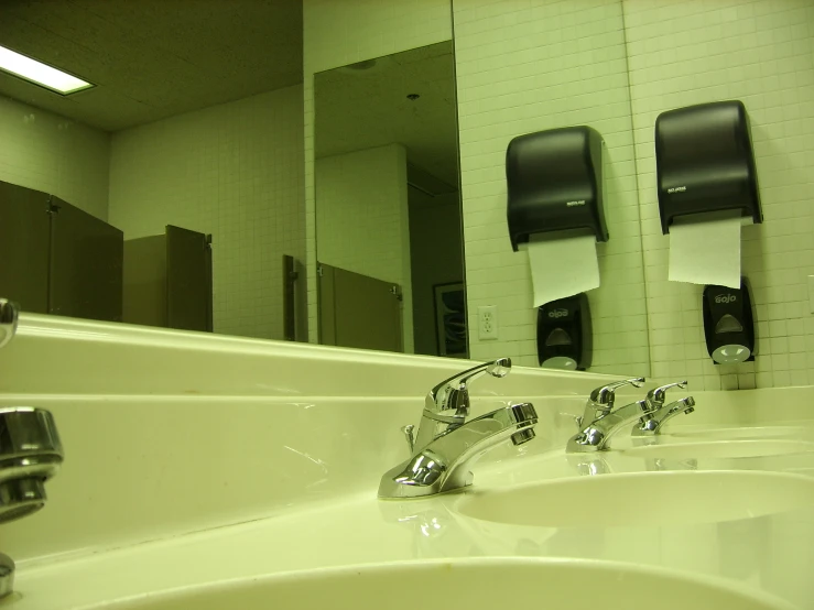 bathroom mirror and sinks with paper towels on them