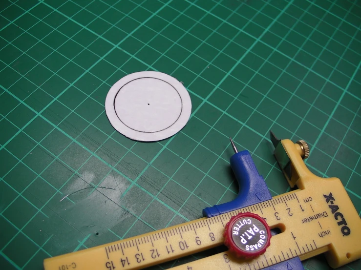 a caliper, tape measure and a hole punch are sitting on a green surface