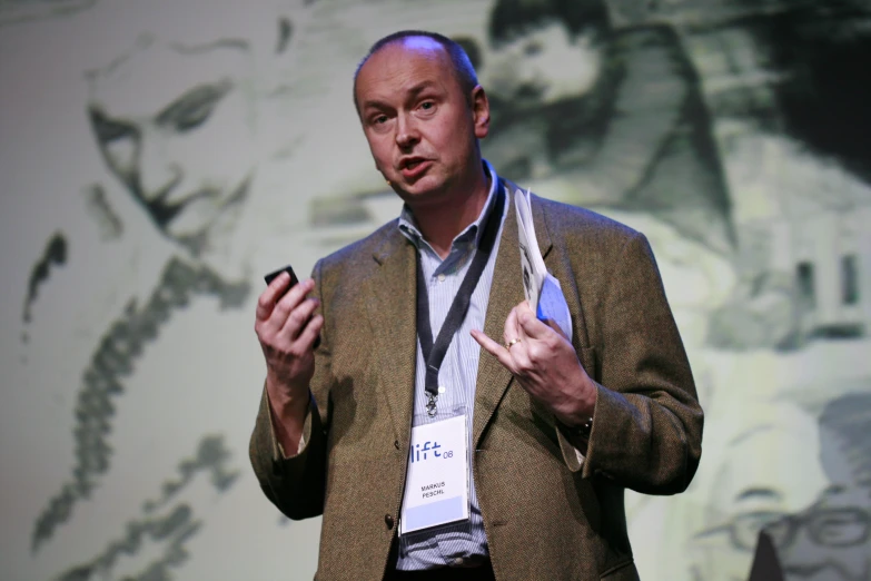 a man holding a smart phone while giving a presentation