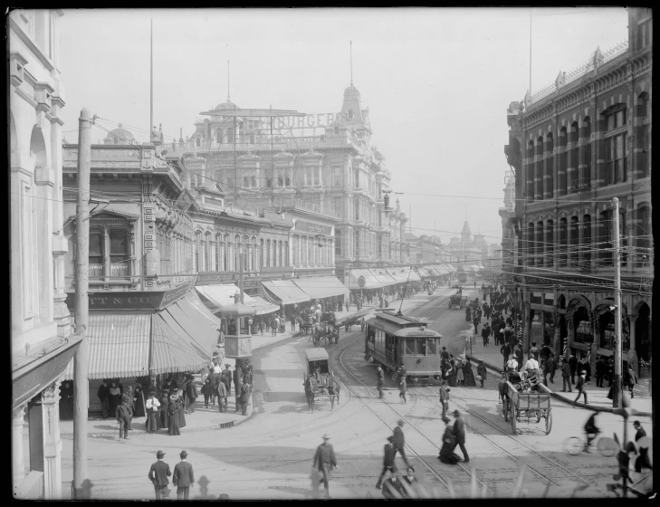 old po of people walking down a street near horse carriages