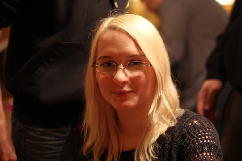 a blonde girl with glasses posing for the camera