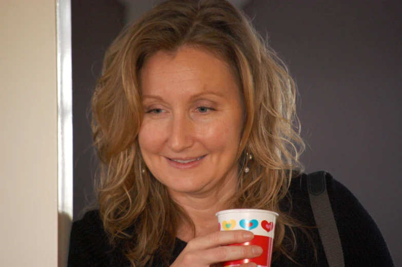 a woman with blonde hair holding a cup of coffee