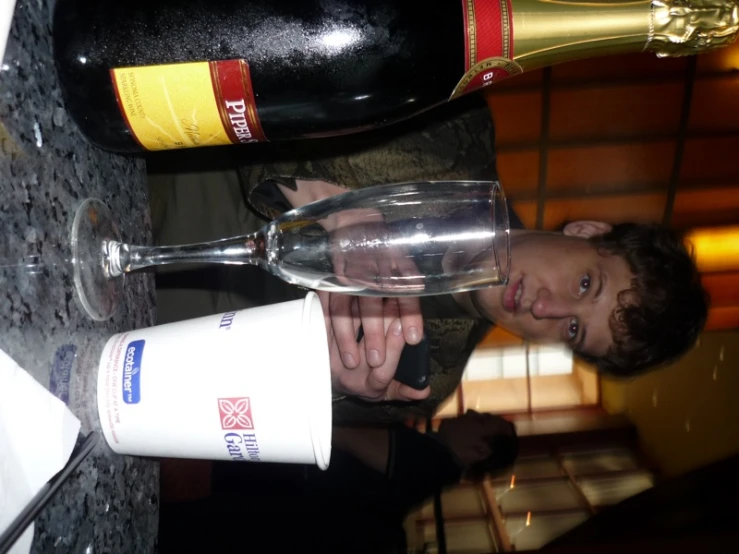 man in front of glass and bottle of wine