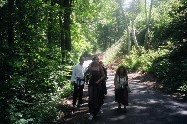 two people walk along a road near trees