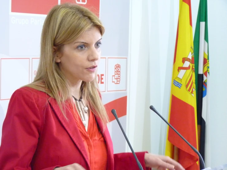 a woman in a red jacket giving a speech