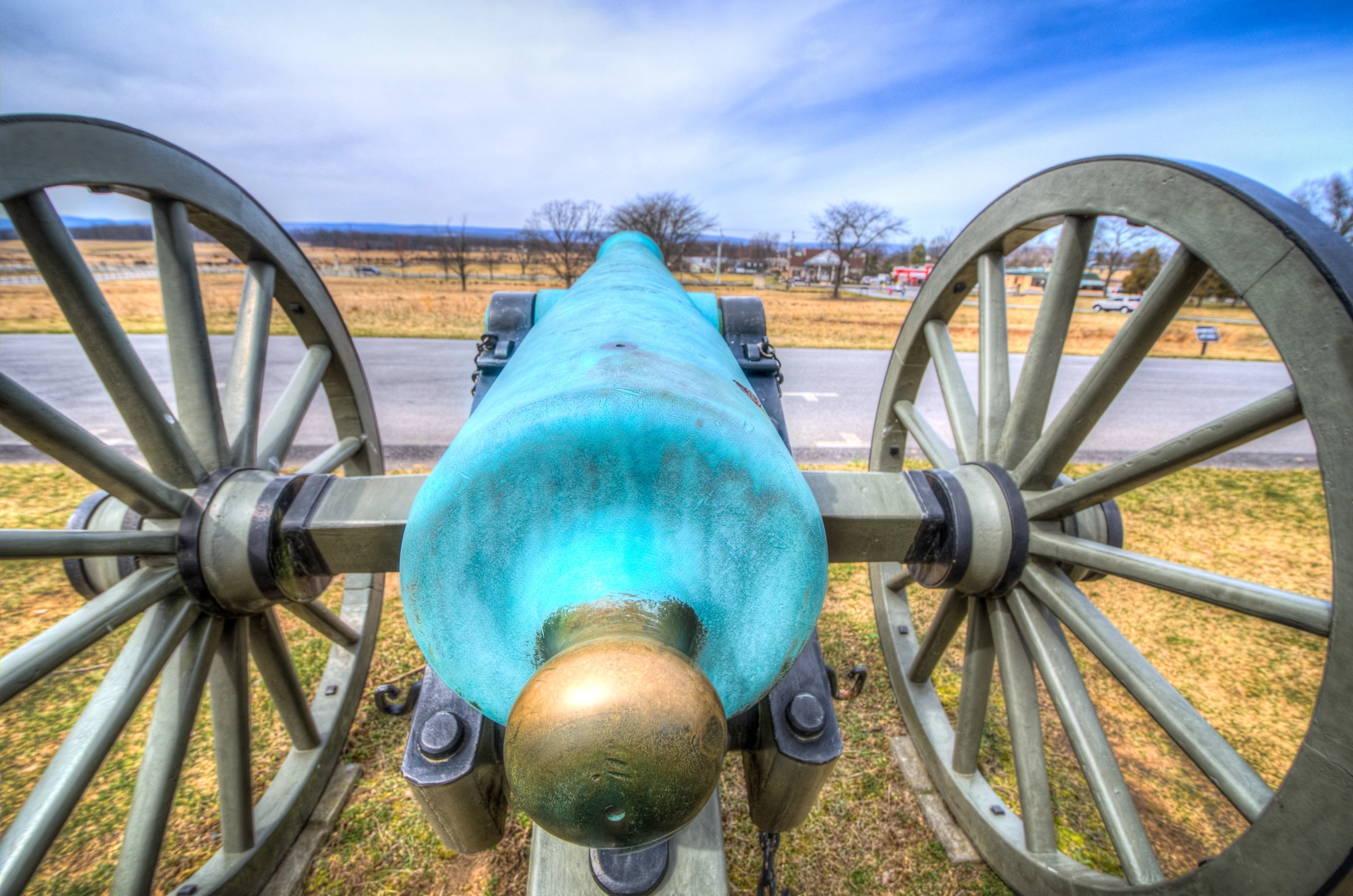 a cannon wheel with an iron top stands at attention on the side of a road