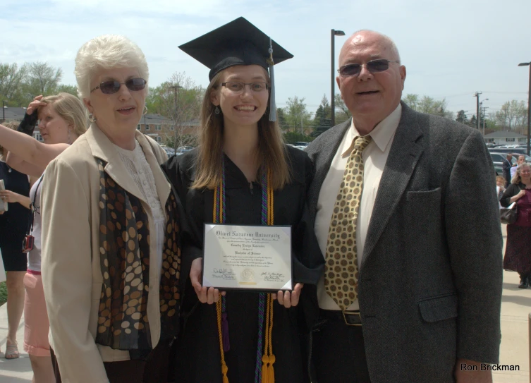 two adults and one child posing with a certificate