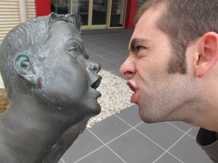 two men kissing a statue of a boy and girl