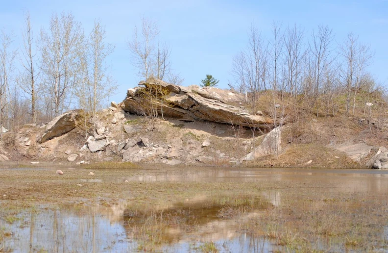 a rock formation along a river bank with low rocks sticking out of the bank