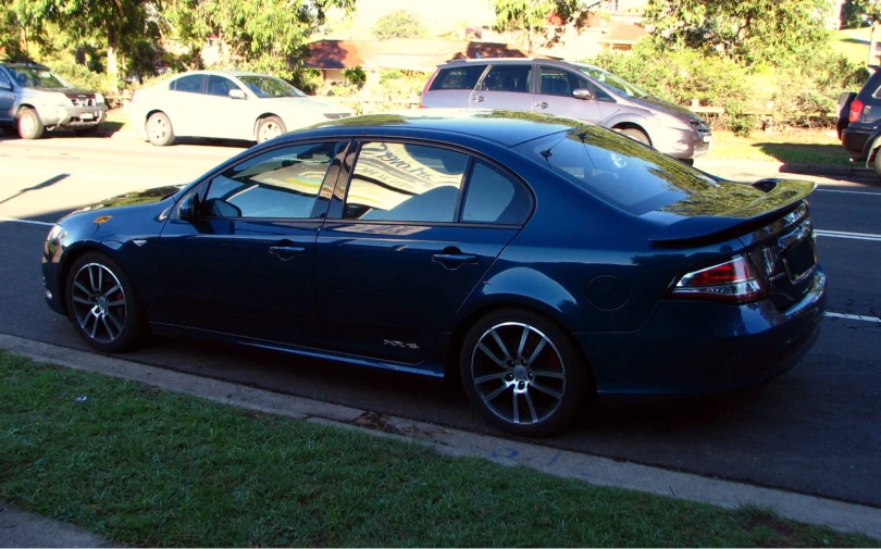 a black car on a city street near trees