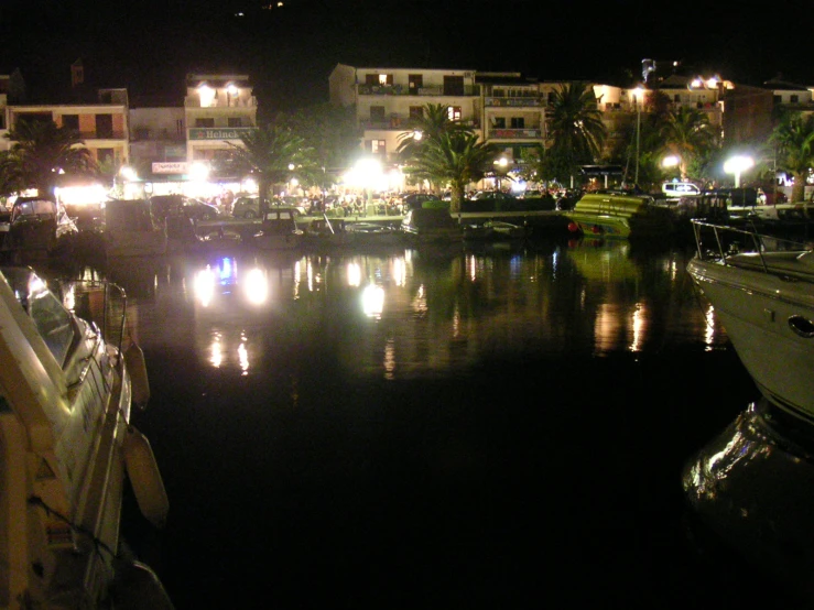 boats are lined up along a river with lights on the buildings