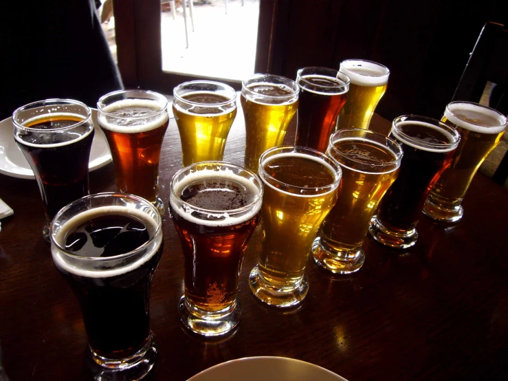 a wooden table topped with lots of tall beer glasses