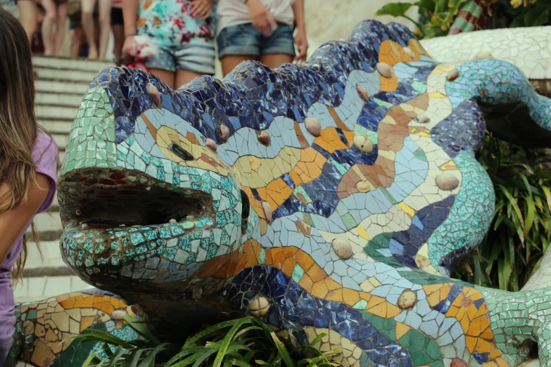 an elephant is painted with colorful tiles near many people