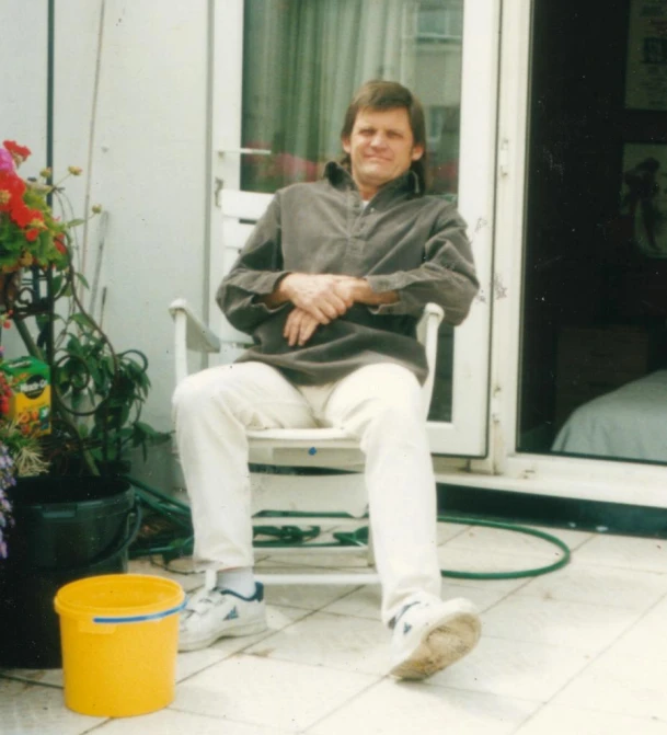 a man sitting on a chair on the outside of his house