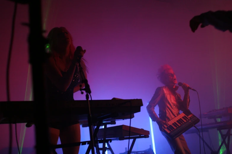 a woman with a keyboard standing in front of a microphone