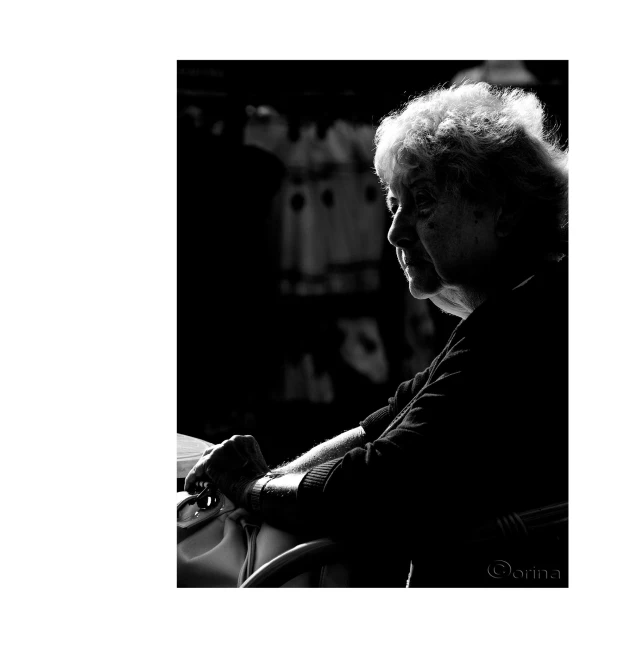 a black and white po of an older woman with grey hair sitting next to a birdhouse