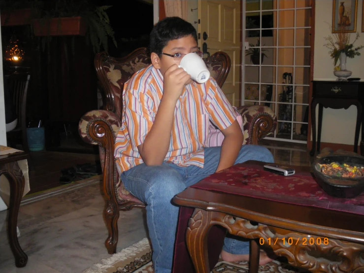 a man sitting in a chair drinking from a paper cup