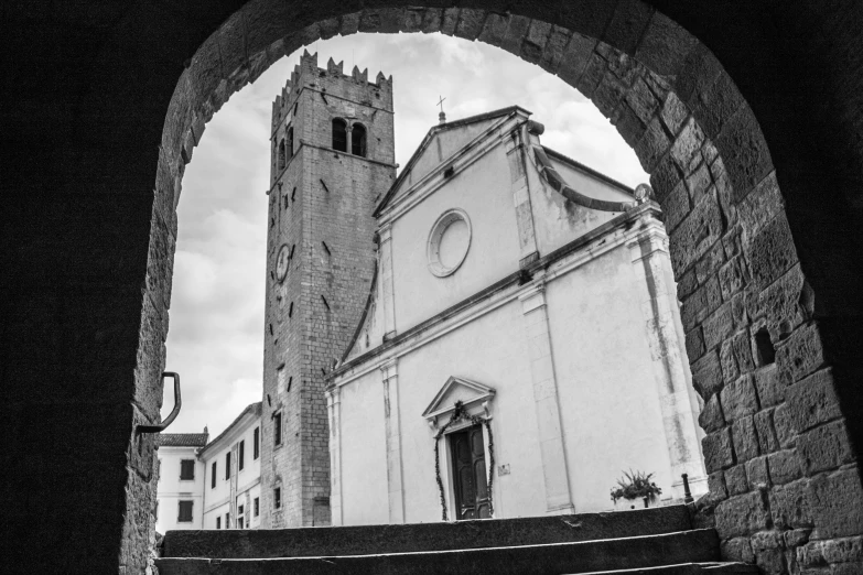 black and white image of a church looking out of a stone archway
