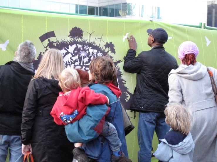 a group of people with children is painting on the wall