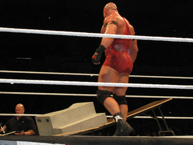 a wrestler in a red suit standing in the ring