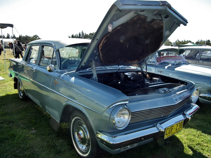 a man and woman looking at an older model car