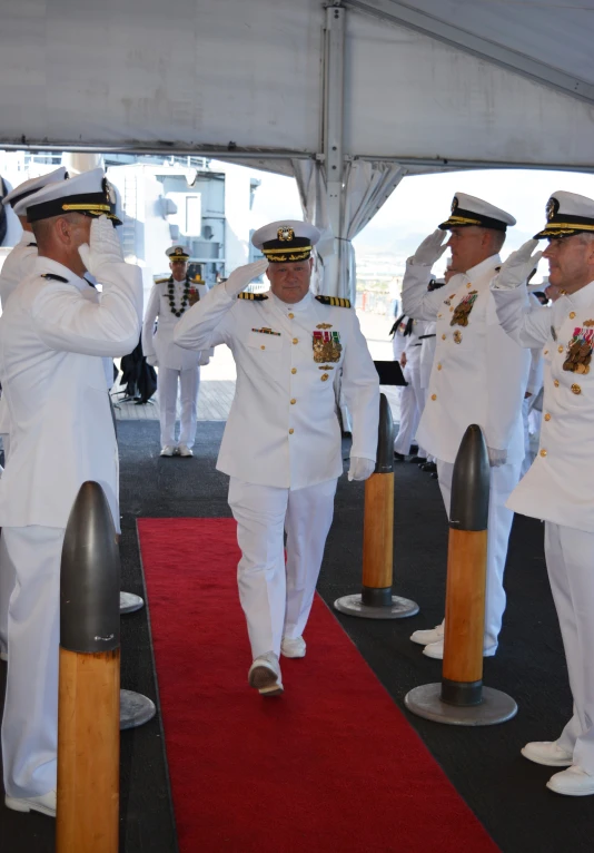 two men in naval uniforms are walking toward each other