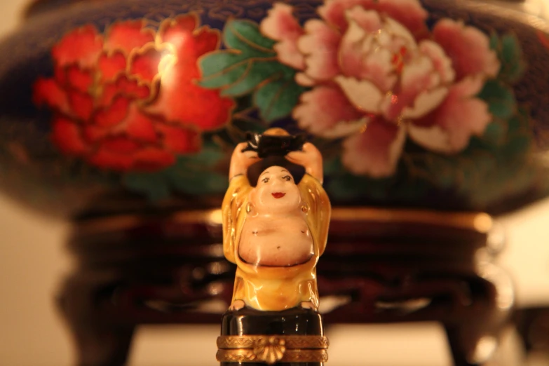 an asian figurine is placed by a decorated vase