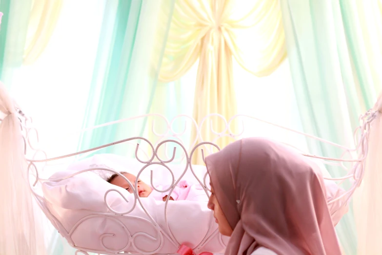 a woman wearing a hijab in bed looking at a baby