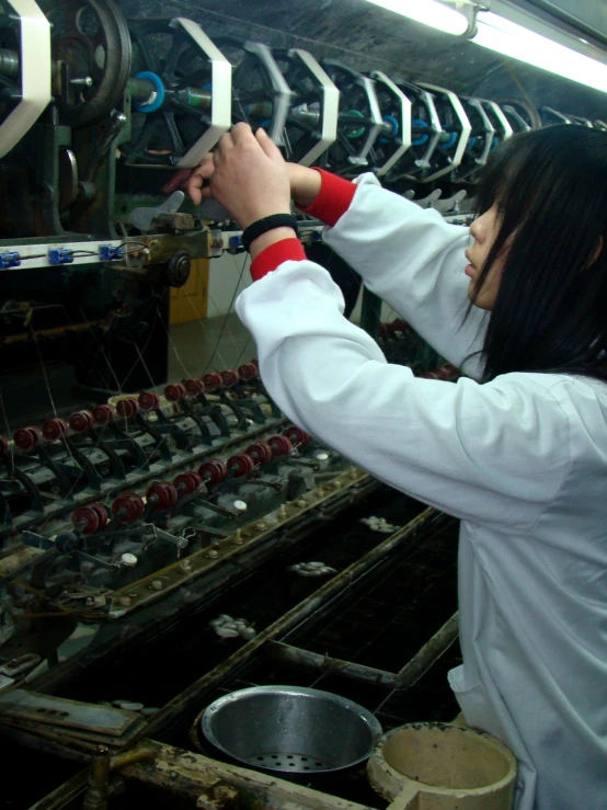 a woman working on machinery inside of a factory