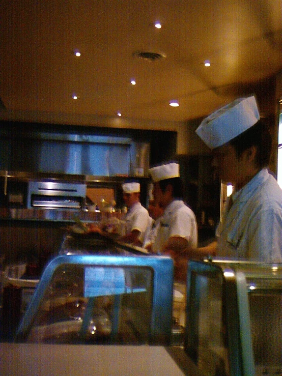 chefs standing at the bar in a kitchen preparing food