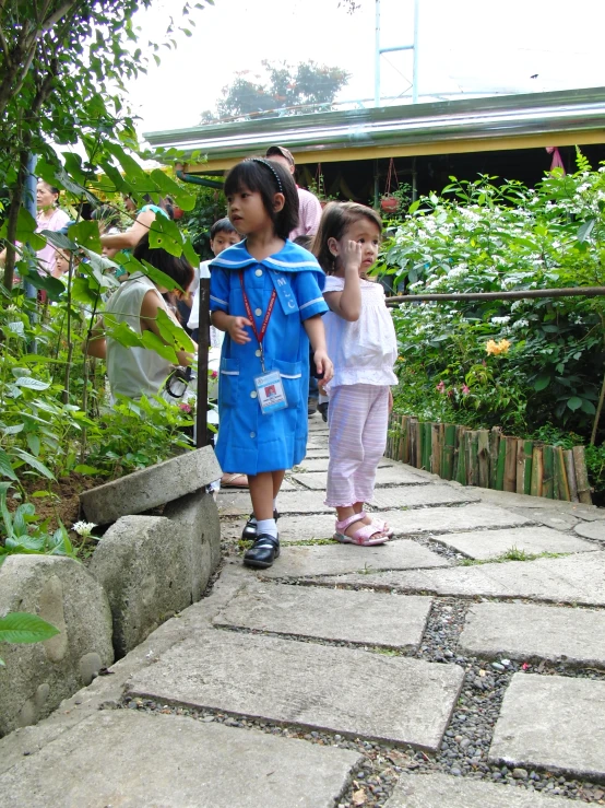 two s walking on cobblestones and some bushes