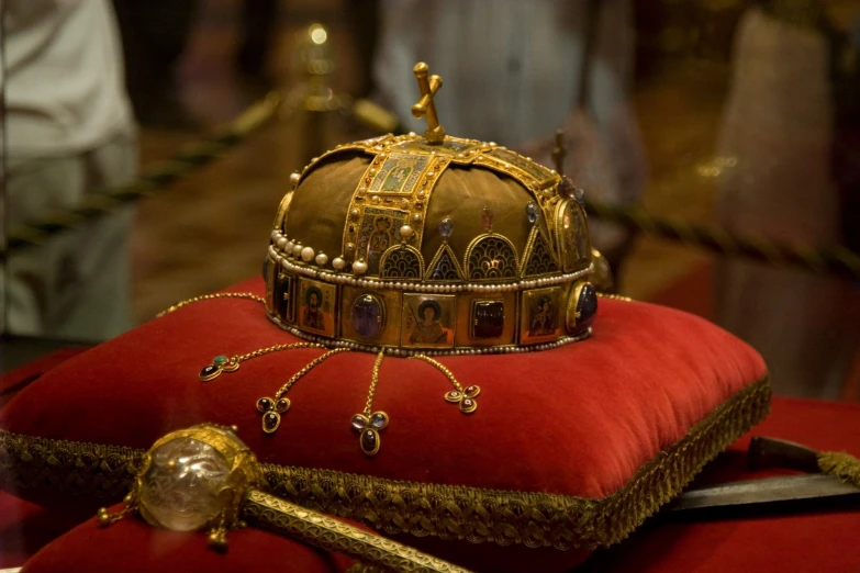 a crown, knife and comb are set on a red cushion