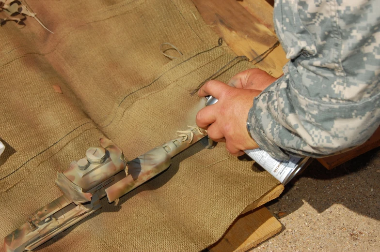 a man in camouflage is using a tool to cut fabric