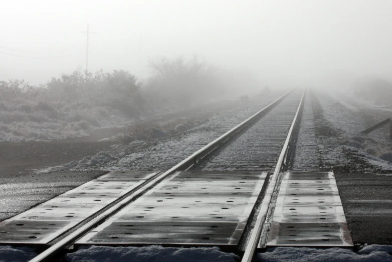 a foggy day along train tracks that are close to an industrial rail