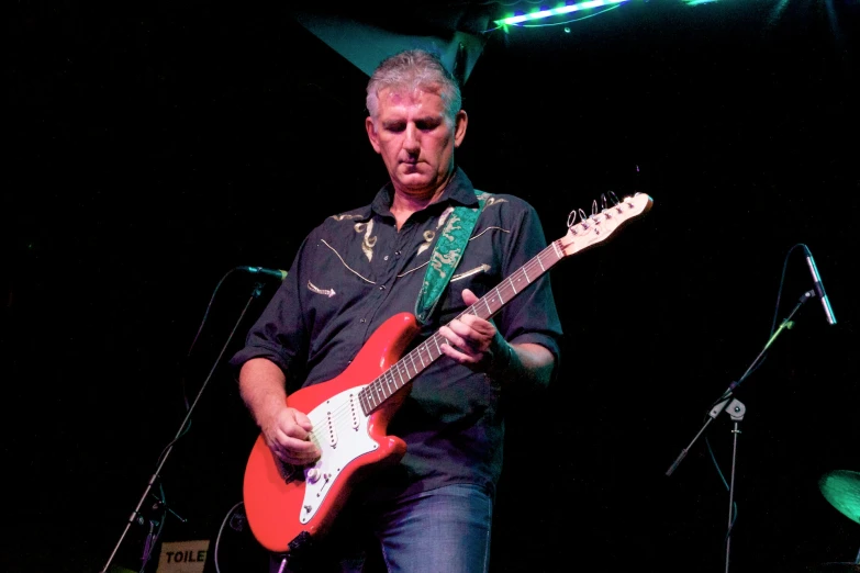 man in black shirt playing guitar on stage