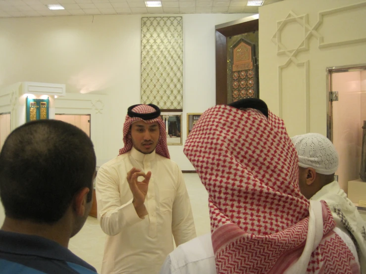 two men talking with others in a mosque