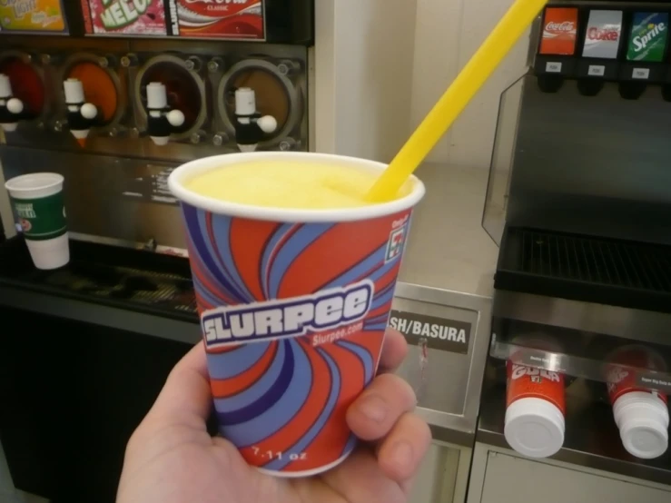 a hand holds a paper cup of a drink with orange, blue and red swirl