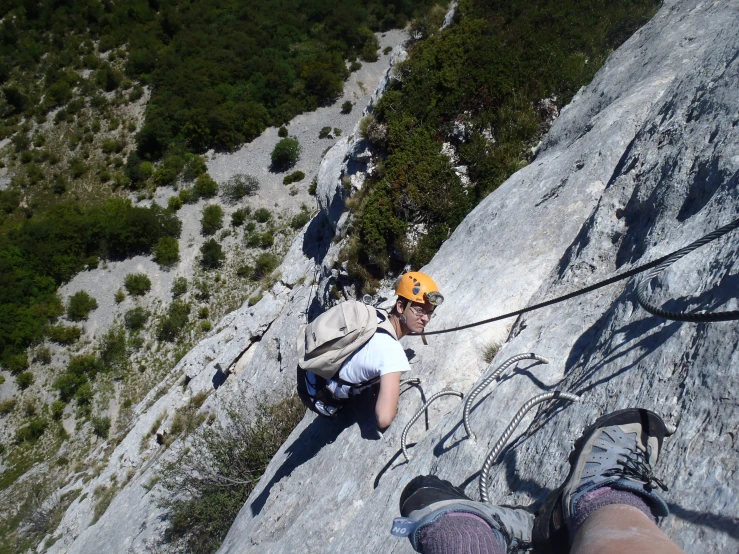 person climbing in a canyon with a helmet on