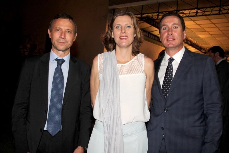 three people stand together in formal clothing for a po