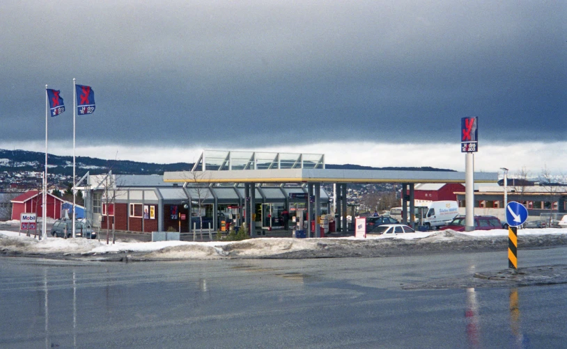 a gas station with many flags flying high on a pole