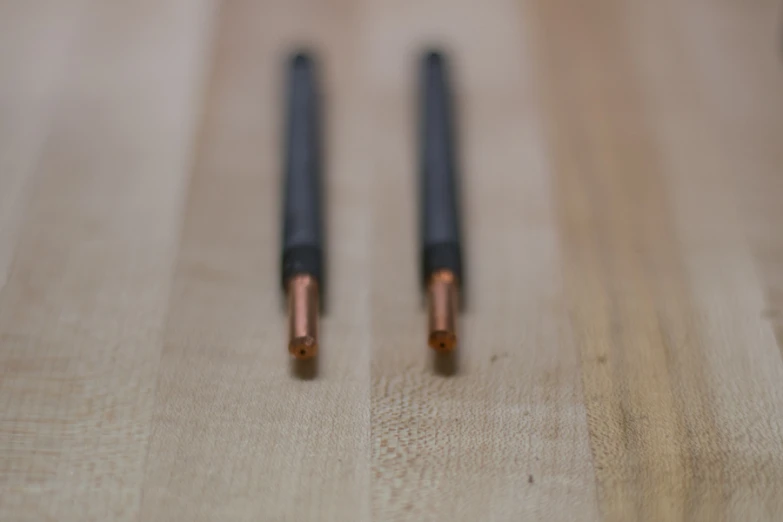 two black pens sitting next to each other on a table