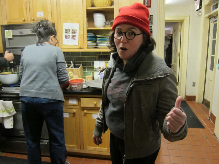 woman standing in a kitchen giving the thumbs up sign