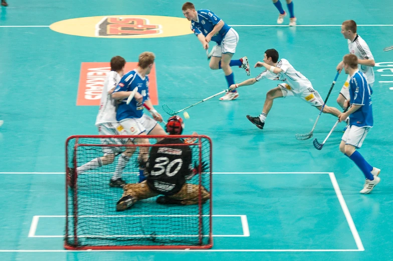 a lacrosse match is in progress as the player is diving over the net