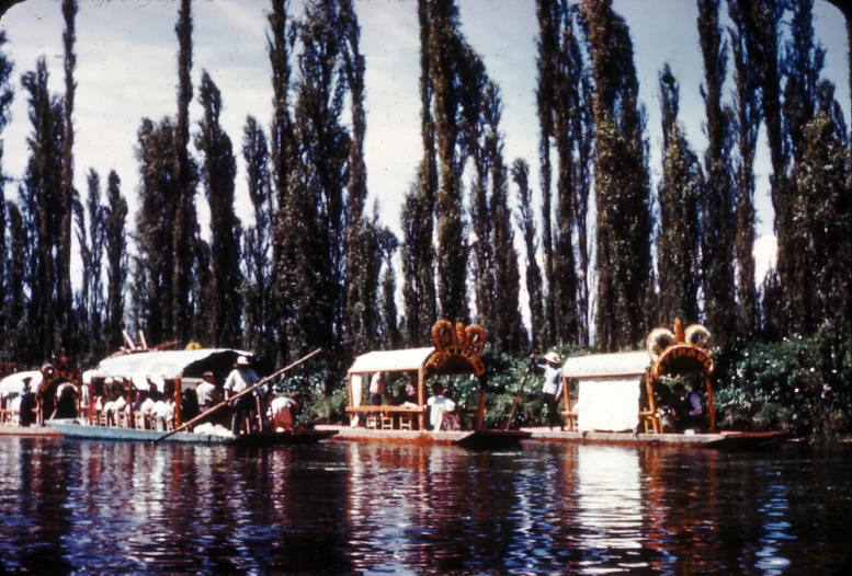 the river is full of people, trees and boats