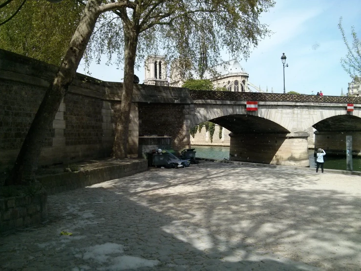 a paved area with cars driving on it, and a bridge in the background