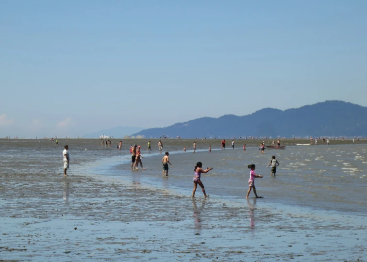 people standing on a beach with mountains in the background