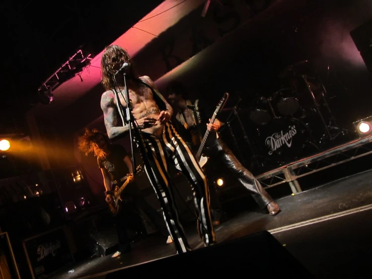 a man holding up a guitar next to two other men on stage